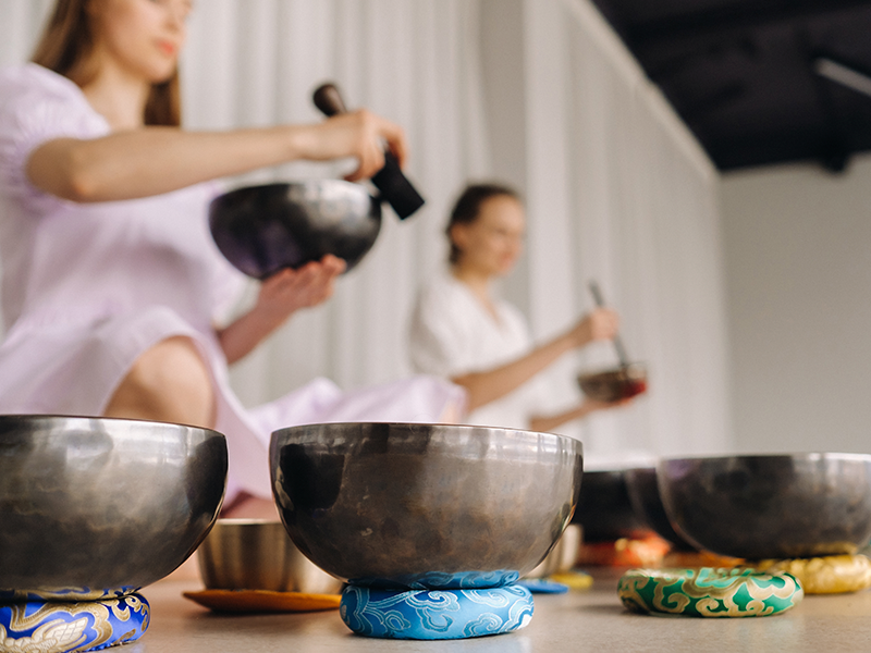 dos-profesoras-de-yoga-juegan-en-cuencos-tibetanos-en-el-gimnasio-durante-un-retiro-de-yoga