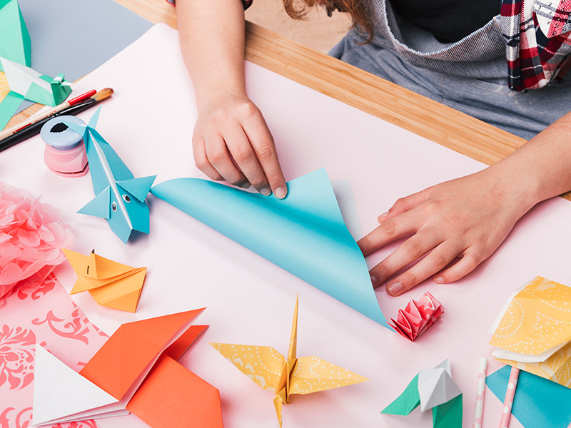 artista-femenina-doblando-papel-de-origami-para-hacer-bellas-artesanias
