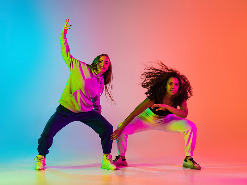 dos-hermosas-chicas-bailando-hiphop-sobre-un-colorido-fondo-degradado-con-luces-de-neon