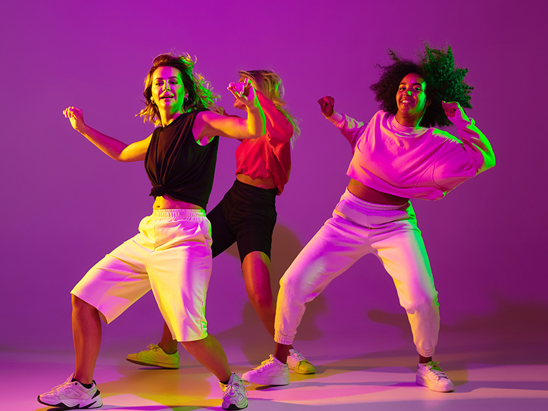 flexible-chicas-deportivas-bailando-hip-hop-con-ropa-elegante-sobre-fondo-rosa-purpura-en-el-salon-de-baile-con-luz-de-neon-verde-cultura-juvenil-movimiento-estilo-y
