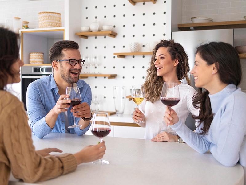 grupo-de-amigos-bebiendo-vino-en-la-cocina