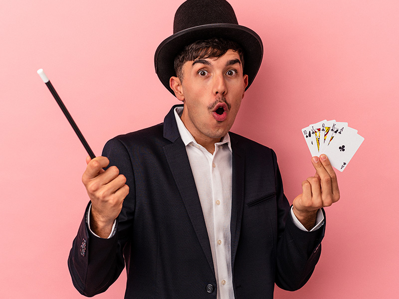 joven-mago-caucasico-sosteniendo-una-varita-magica-y-tarjetas-magicas-aislado-sobre-fondo-blanco