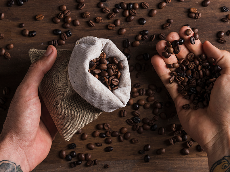 manos-sosteniendo-sacos-y-granos-de-cafe