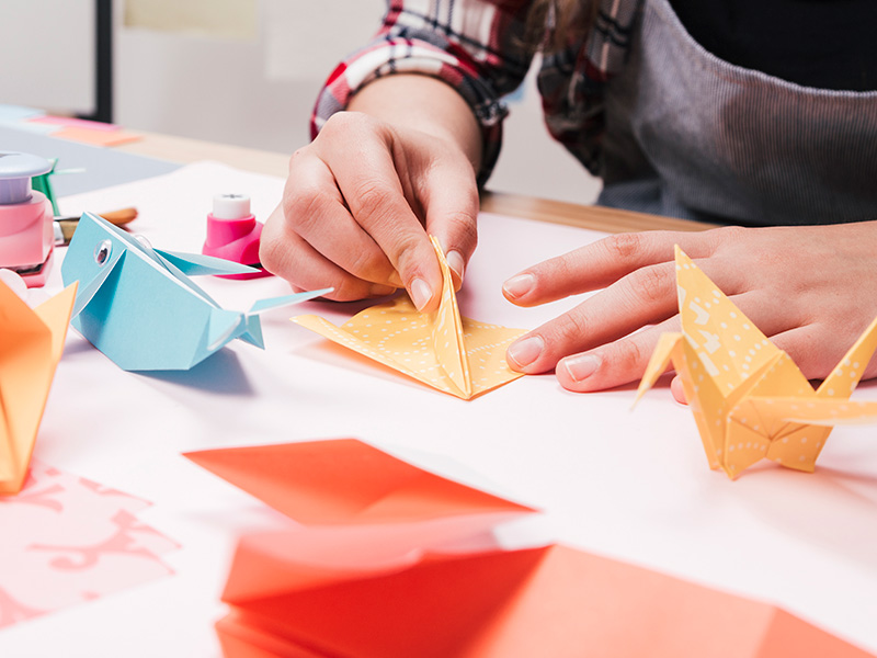 primer-plano-de-la-mano-de-la-mujer-que-hace-arte-creativo-del-arte-usando-el-papel-del-origami