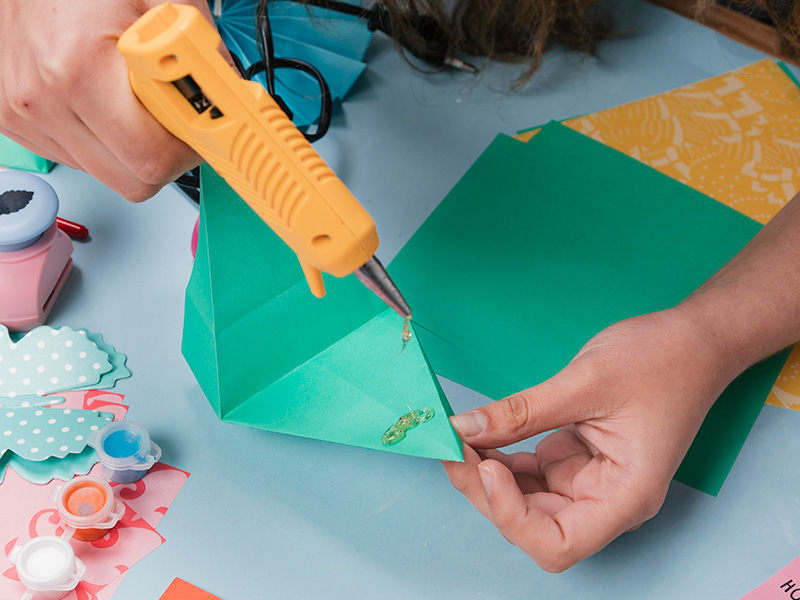 primer-plano-de-una-mujer-que-usa-una-pistola-de-pegamento-caliente-mientras-hace-arte