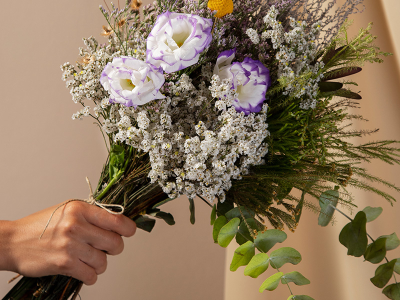 vista-lateral-mano-sosteniendo-hermosas-flores