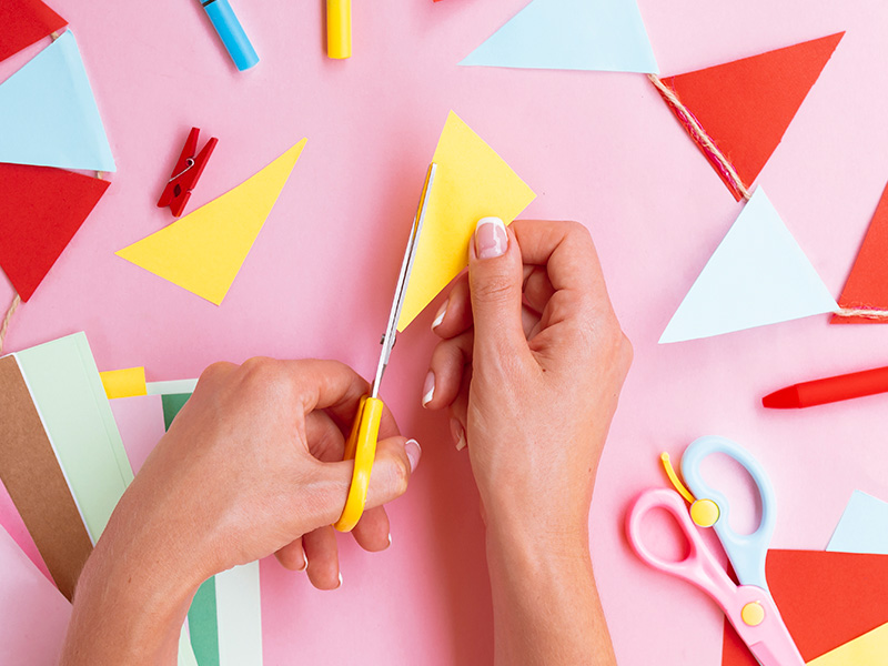 vista-superior-de-mujer-cortando-papel-de-color