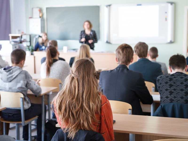 vista-trasera-de-los-estudiantes-sentados-en-el-aula